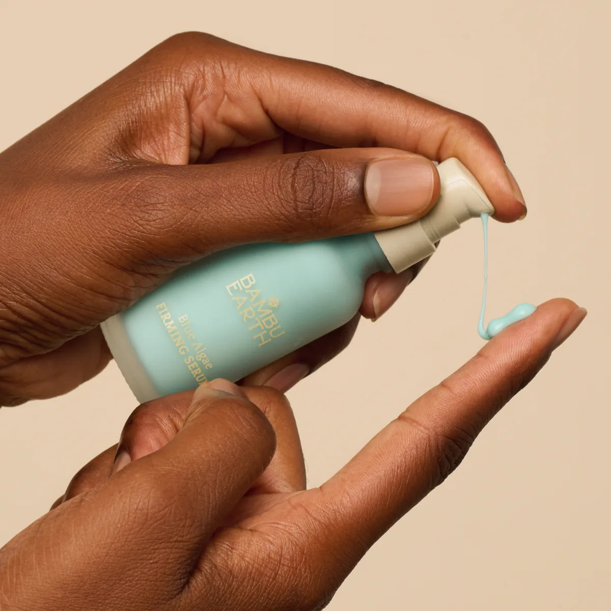 Hands pumping the pale blue serum onto a fingertip