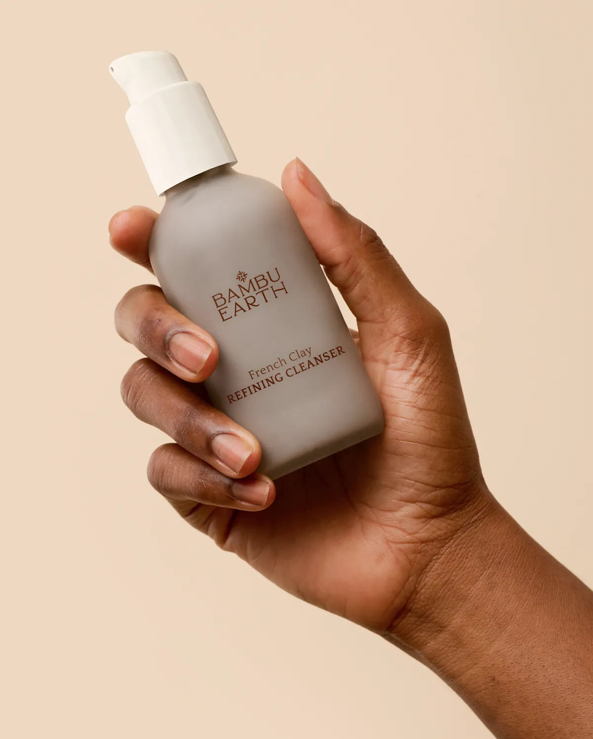Hand holding the 4 oz French Clay Refining Cleanser pump bottle