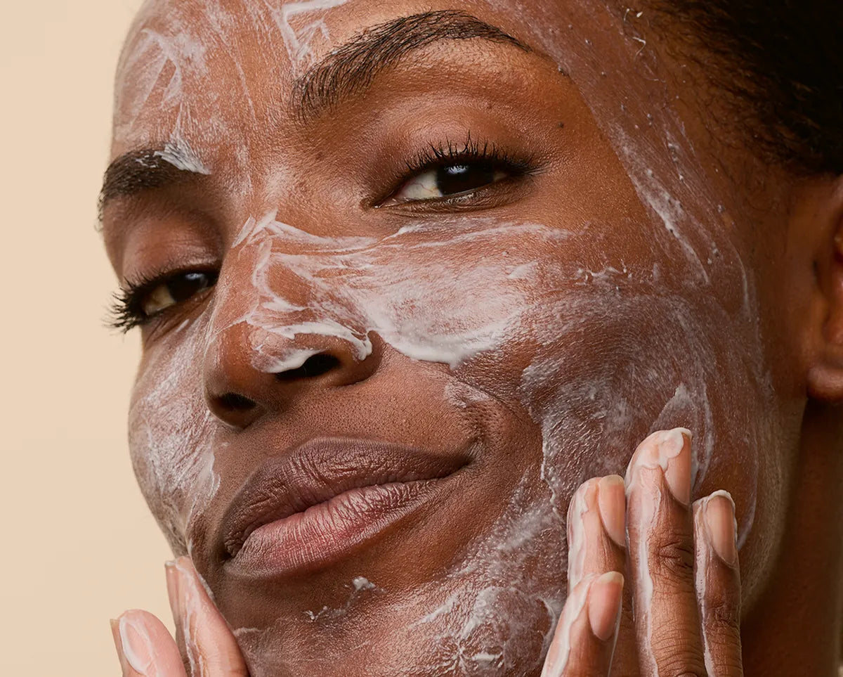 Person massaging the cream cleanser onto damp skin