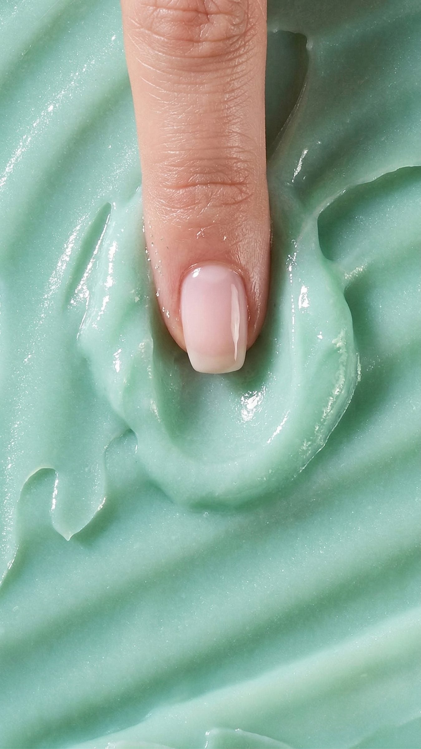 Macro of a fingertip pressing into the soft blue-green balm